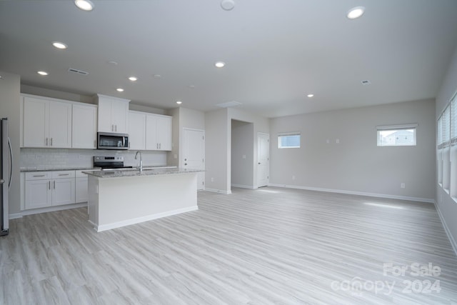 kitchen featuring light stone counters, an island with sink, light hardwood / wood-style flooring, white cabinetry, and stainless steel appliances