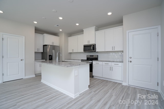 kitchen with white cabinets, a center island with sink, and stainless steel appliances