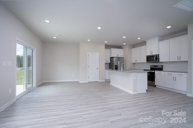 kitchen with light hardwood / wood-style flooring, white cabinets, appliances with stainless steel finishes, and a kitchen island with sink