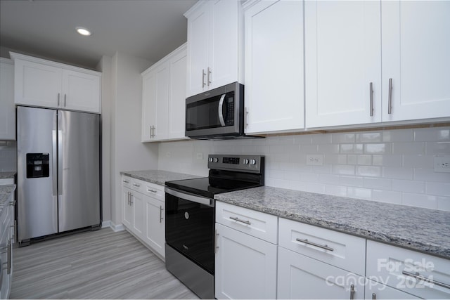 kitchen with white cabinets, appliances with stainless steel finishes, light stone countertops, and decorative backsplash