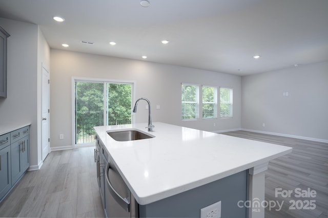 kitchen featuring gray cabinetry, sink, plenty of natural light, and an island with sink