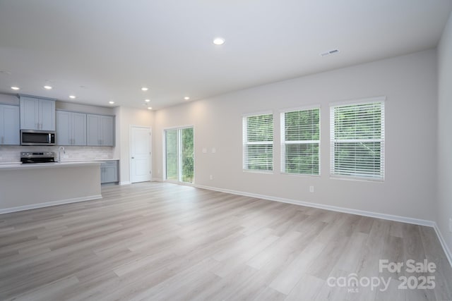 unfurnished living room featuring plenty of natural light and light wood-type flooring