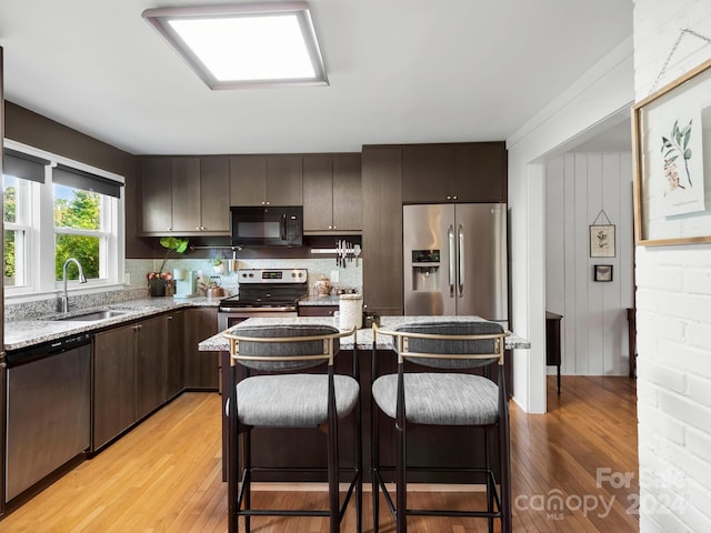 kitchen featuring backsplash, appliances with stainless steel finishes, light hardwood / wood-style flooring, dark brown cabinetry, and sink