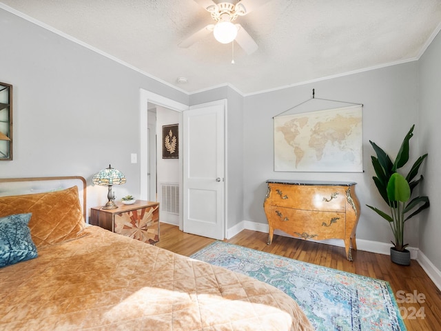 bedroom with ceiling fan, hardwood / wood-style flooring, ornamental molding, and a textured ceiling