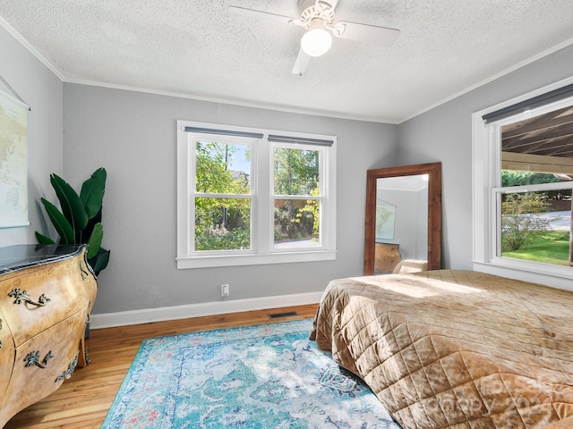 bedroom featuring crown molding, a textured ceiling, light wood-type flooring, and ceiling fan