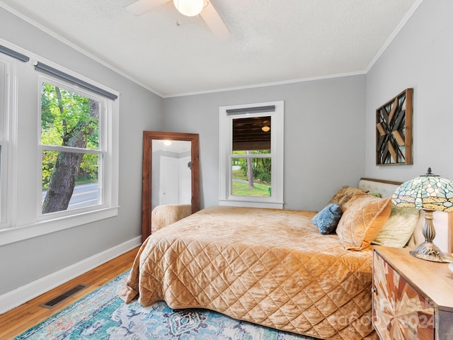 bedroom with multiple windows, hardwood / wood-style flooring, crown molding, and ceiling fan