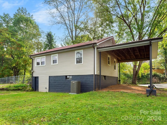 view of side of home with cooling unit, a lawn, and a carport