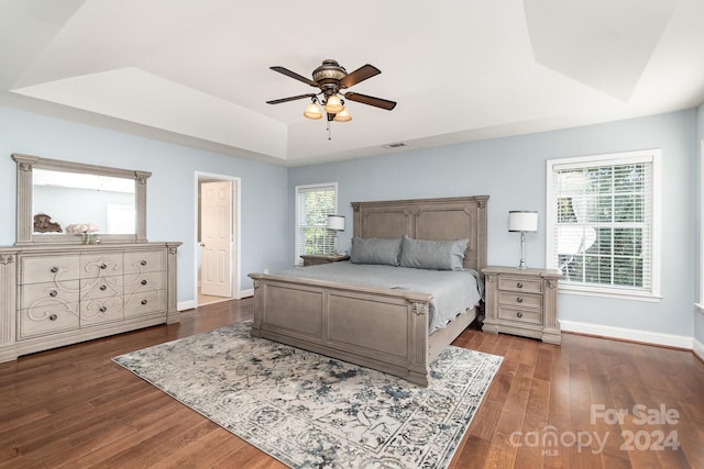 bedroom with a raised ceiling, dark hardwood / wood-style floors, and ceiling fan