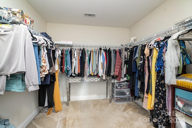 walk in closet with light colored carpet