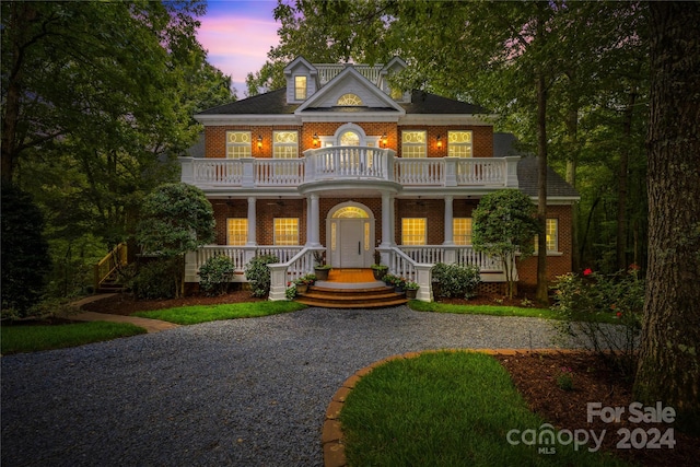 greek revival inspired property with a balcony and covered porch