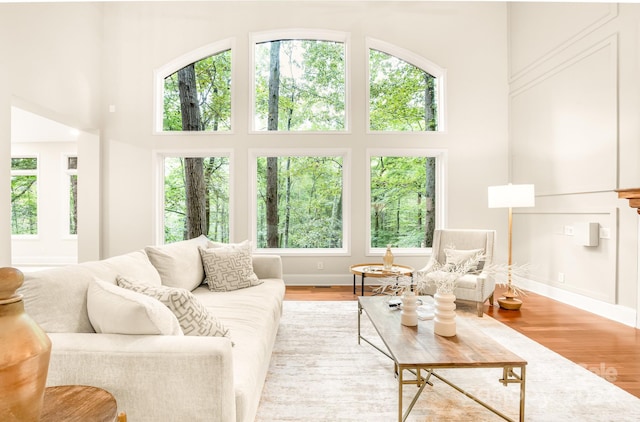 living room featuring light wood-type flooring and a towering ceiling