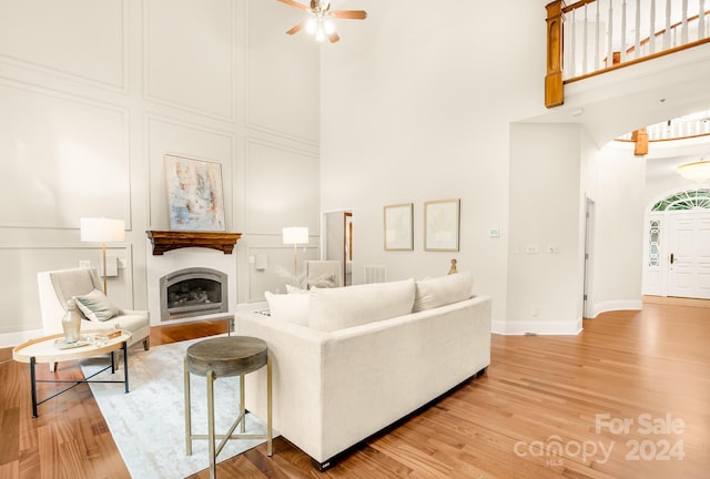 living room with ceiling fan, a high ceiling, and wood-type flooring