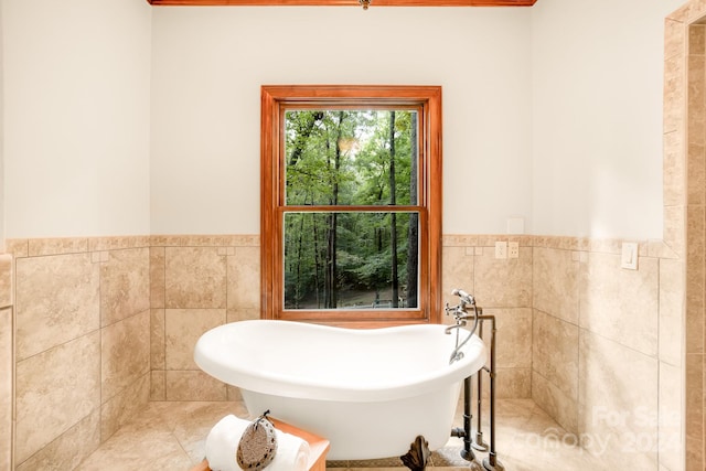 bathroom with a tub to relax in, tile walls, and tile patterned floors