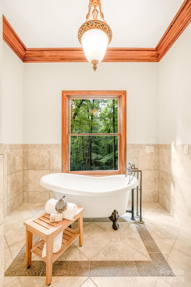 bathroom with a bath, crown molding, and tile walls