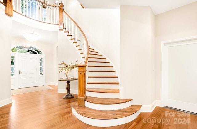 foyer with light hardwood / wood-style flooring, a towering ceiling, and an inviting chandelier