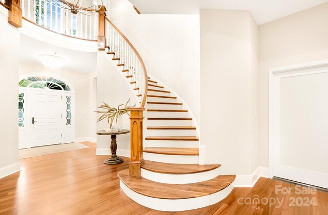 10250 Barringer Ct, Mount Pleasant, NC 28124 - staircase with baseboards, wood finished floors, a towering ceiling, and an inviting chandelier