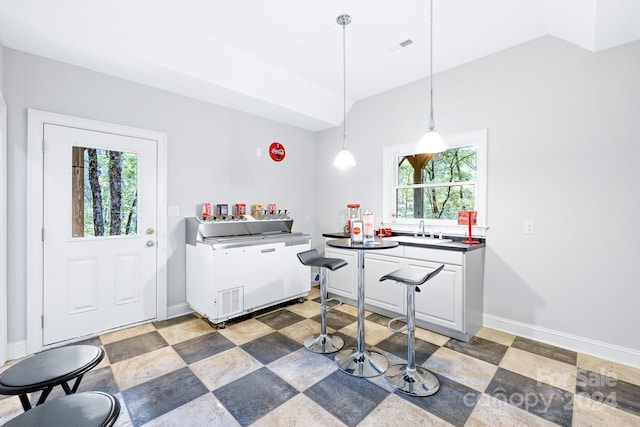 10250 Barringer Ct, Mount Pleasant, NC 28124 - kitchen with white cabinetry, decorative light fixtures, lofted ceiling, baseboards, and a sink