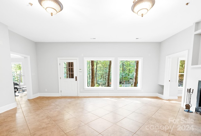 unfurnished living room with light tile patterned flooring and a healthy amount of sunlight