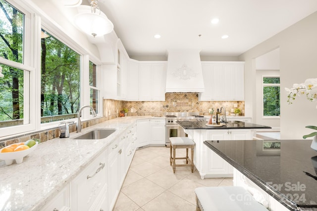 kitchen with a wealth of natural light, premium range hood, dark stone counters, and a kitchen island