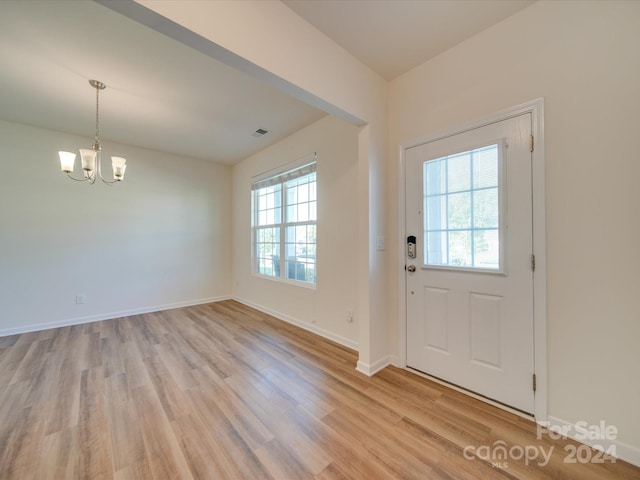 foyer entrance with a wealth of natural light, a chandelier, and light wood-type flooring