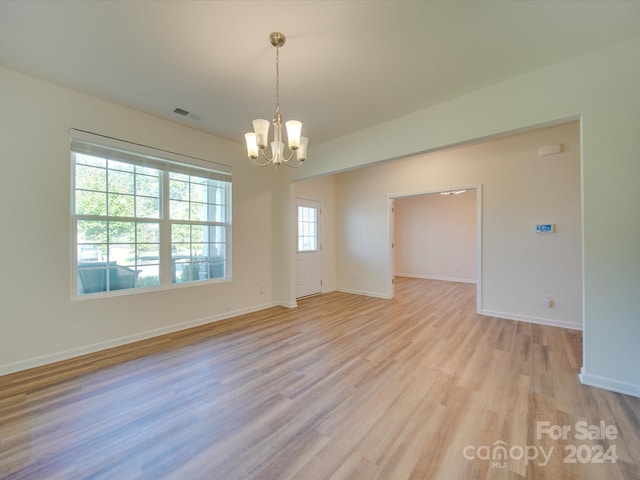 empty room featuring light hardwood / wood-style floors and a chandelier