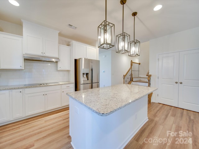 kitchen with hanging light fixtures, stainless steel fridge, a center island, light wood-type flooring, and white cabinetry