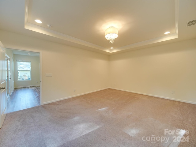 carpeted empty room featuring ornamental molding and a tray ceiling