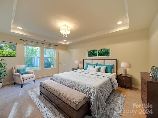 bedroom with light carpet and a raised ceiling