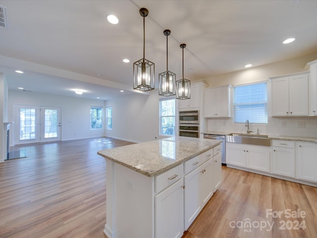 kitchen featuring hanging light fixtures, sink, a center island, light wood-type flooring, and white cabinets