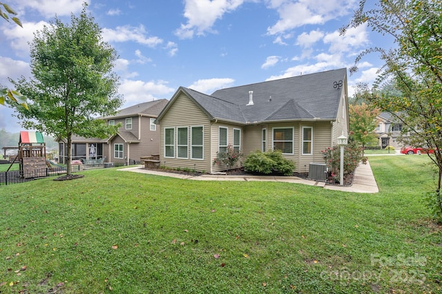 back of house with central AC, a lawn, and a playground