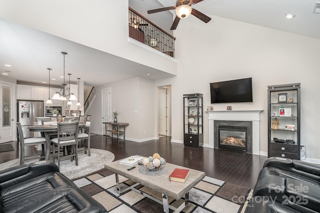 living room with ceiling fan, dark hardwood / wood-style flooring, and a high ceiling