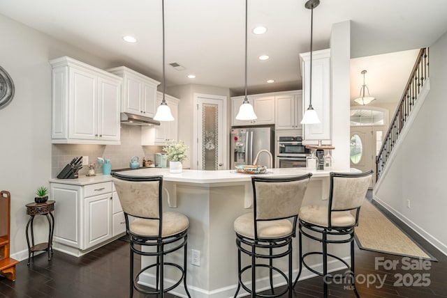 kitchen with hanging light fixtures, white cabinetry, stainless steel fridge, and dark hardwood / wood-style flooring