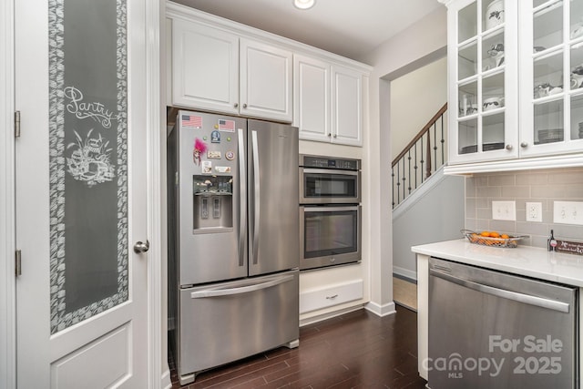 kitchen with white cabinetry, stainless steel appliances, dark hardwood / wood-style floors, and backsplash