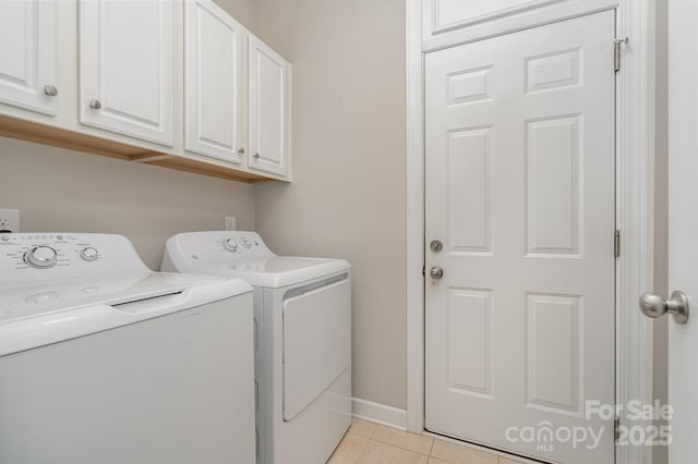 clothes washing area with cabinets, light tile patterned floors, and washing machine and clothes dryer