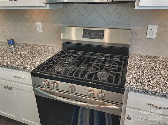 kitchen featuring light stone counters, white cabinetry, tasteful backsplash, and stainless steel range with gas stovetop