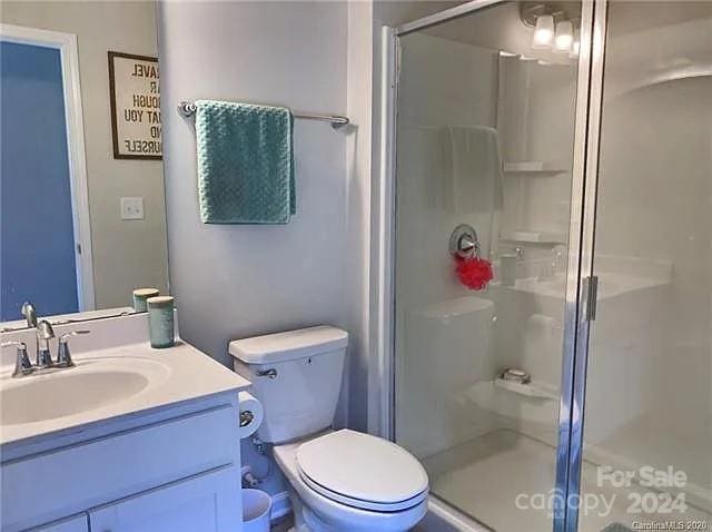 bathroom featuring walk in shower, vanity, and toilet