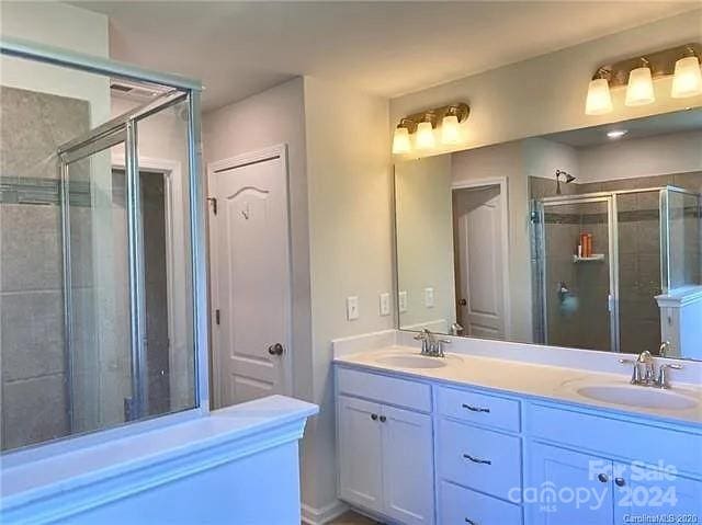 bathroom featuring a shower with door and vanity