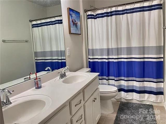 bathroom featuring tile patterned floors, a shower with curtain, vanity, and toilet