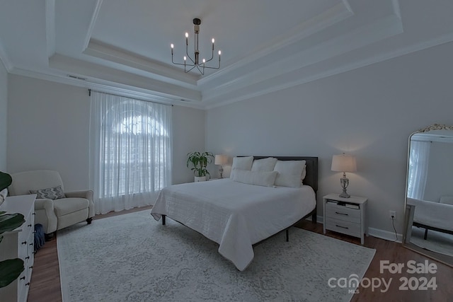 bedroom with a notable chandelier, wood-type flooring, a tray ceiling, and ornamental molding