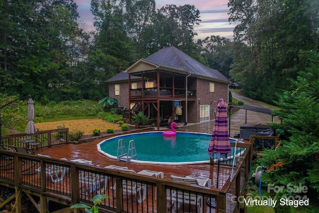 pool at dusk featuring a wooden deck and a patio area