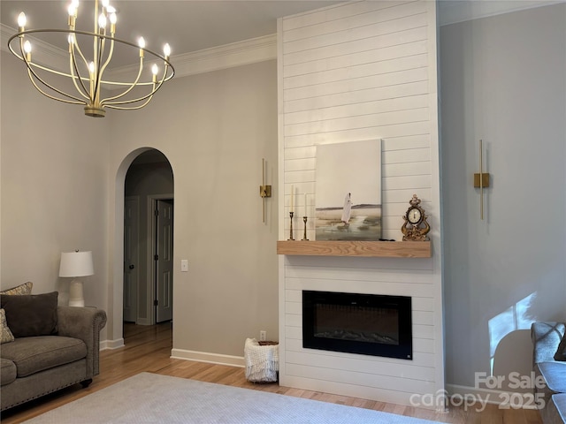 10604 Russet Pl, Charlotte, NC 28227 - living room with wood finished floors, arched walkways, a fireplace, a chandelier, and ornamental molding