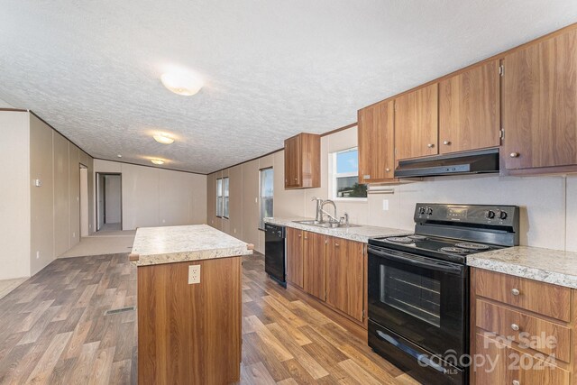 kitchen featuring light wood-type flooring, black appliances, a center island, and extractor fan