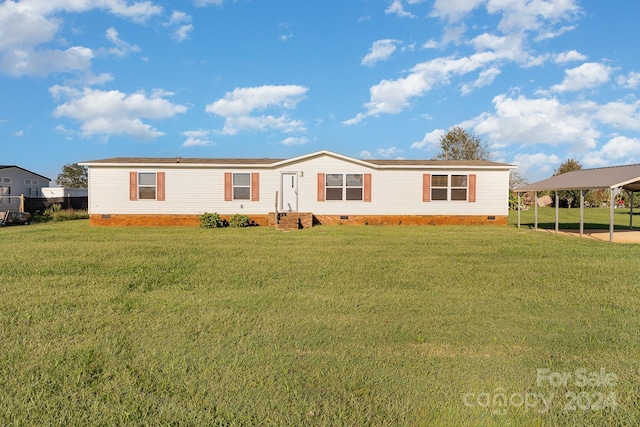 manufactured / mobile home featuring a front yard and a carport