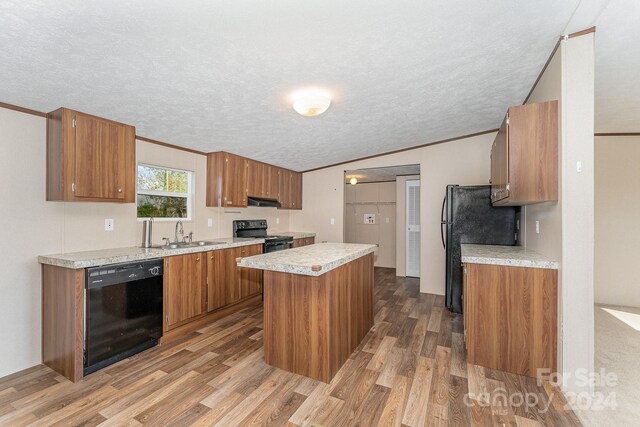 kitchen with ornamental molding, sink, a kitchen island, light hardwood / wood-style flooring, and black appliances