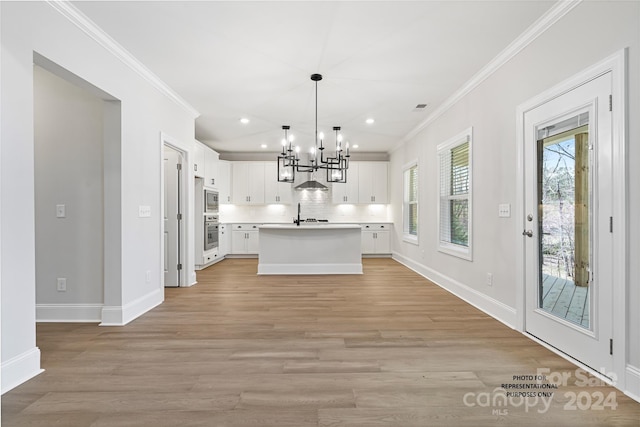 kitchen featuring a kitchen island with sink, hanging light fixtures, appliances with stainless steel finishes, light hardwood / wood-style floors, and white cabinetry