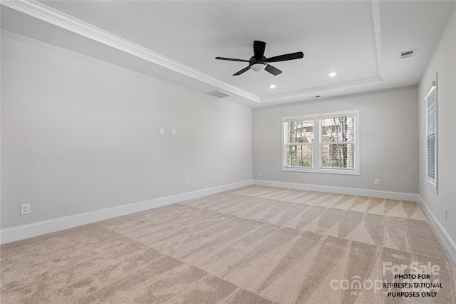 carpeted spare room with ceiling fan, ornamental molding, and a tray ceiling