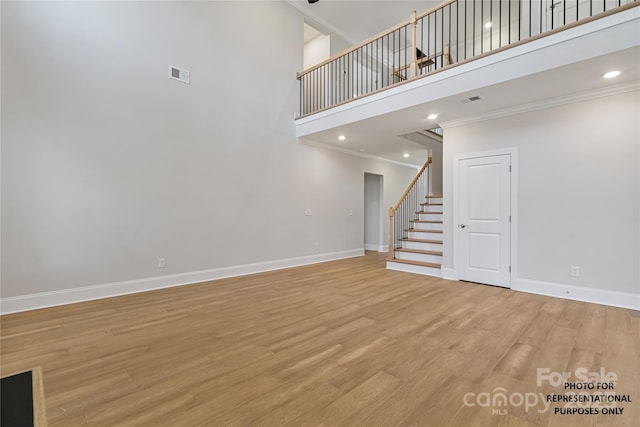 8605 Carly Ln, Mint Hill, NC 28227 - unfurnished living room with stairs, a towering ceiling, ornamental molding, baseboards, and light wood-style flooring
