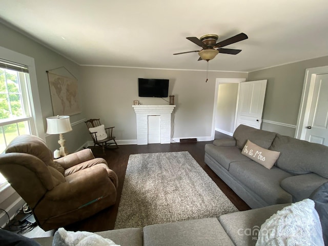 living room featuring ceiling fan, a fireplace, and dark wood-type flooring