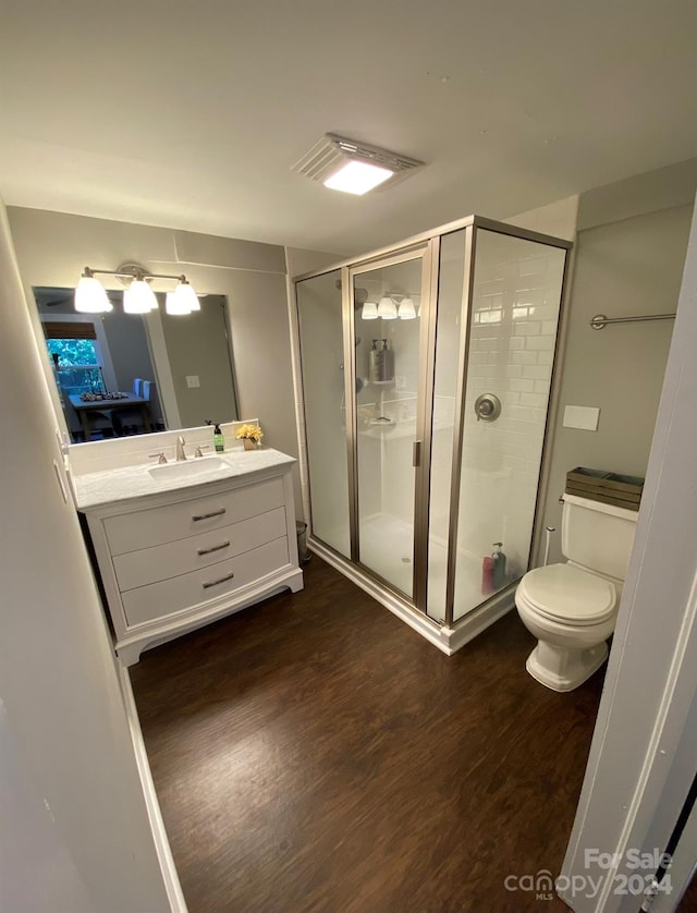 bathroom with vanity, hardwood / wood-style flooring, an enclosed shower, and toilet