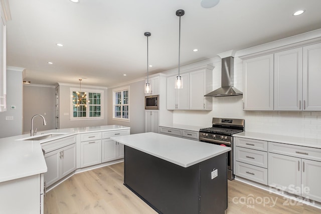 2305 Sanders Ave, Charlotte, NC 28216 - kitchen with a center island, a sink, light wood finished floors, appliances with stainless steel finishes, and wall chimney exhaust hood